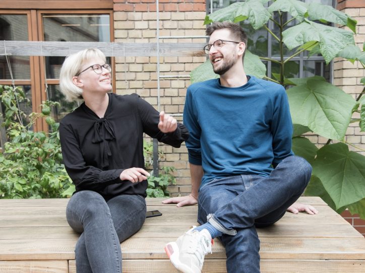 A woman and a man sitting on a bench having a cheerful conversation