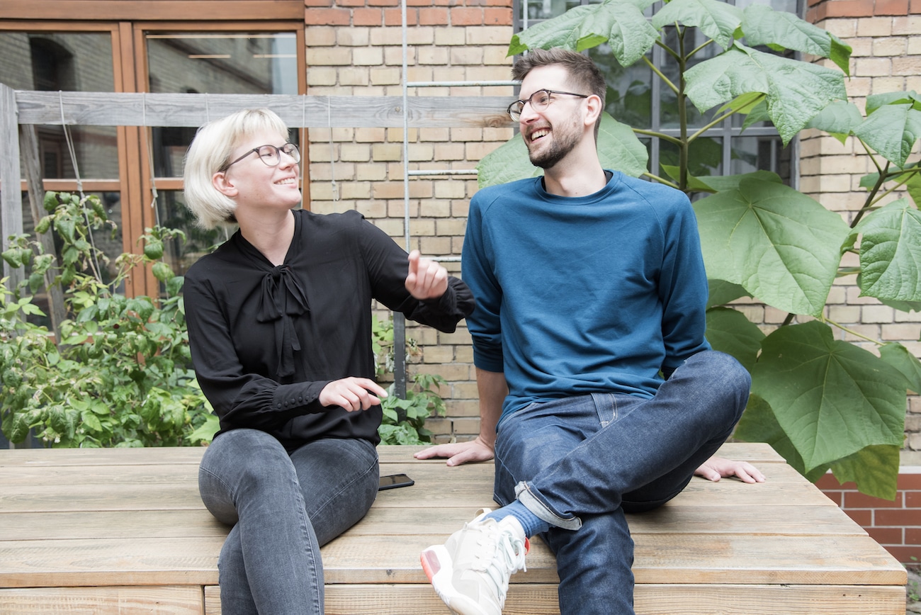 Eine Frau und ein Mann sitzen auf einer Bank und führen eine fröhliche Konversation