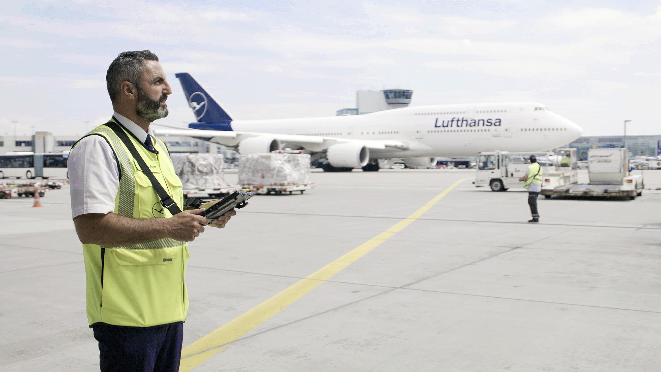 Mann mit gelber Weste und Device in den Händen auf einem Flughafen