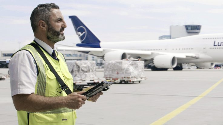 A Lufthansa employee is standing on an airfield