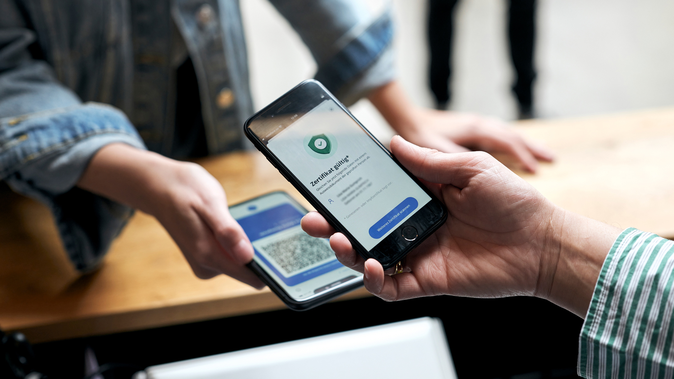 zwei Hände, die jeweils ein Smartphone halten mit geöffneter CovPass-App