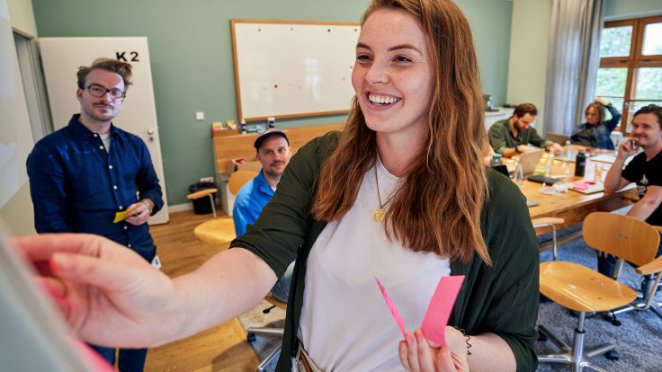 woman standing at whiteboard with post-its in her hand