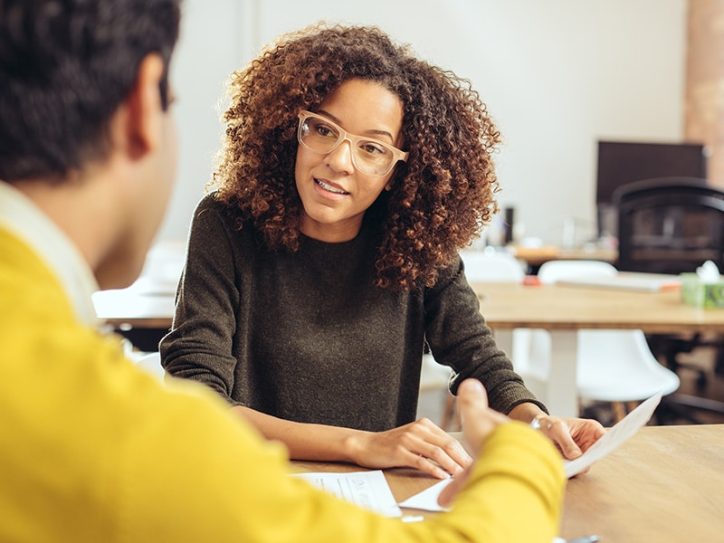 Eine Frau und ein Mann sitzen am Tisch und schauen auf ein Dokument